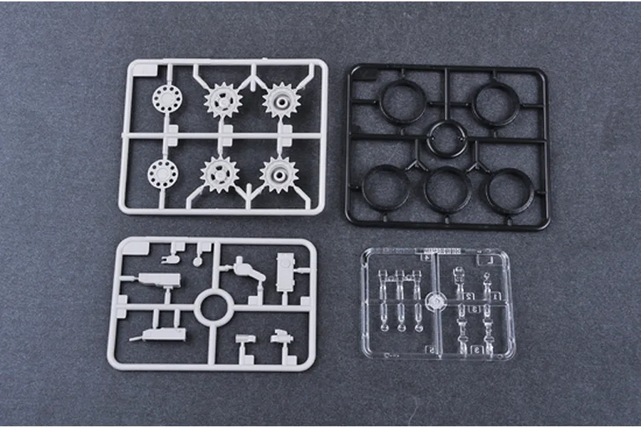 Four plastic model kit sprues including grey, black, and clear parts for a T-62 tank model.