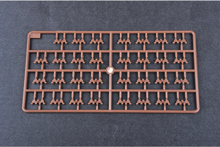 A brown plastic model kit sprue containing multiple small tank track link parts on a dark grey background.