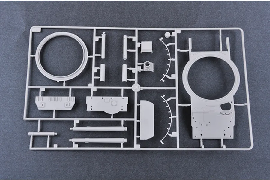 A grey plastic model kit sprue containing various tank parts, including a turret ring and hull components, against a dark grey background.