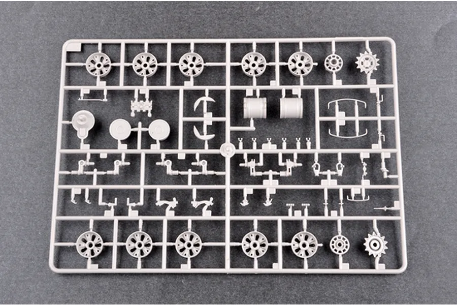 A grey plastic model kit sprue containing various tank parts, including road wheels, sprockets, and suspension components.