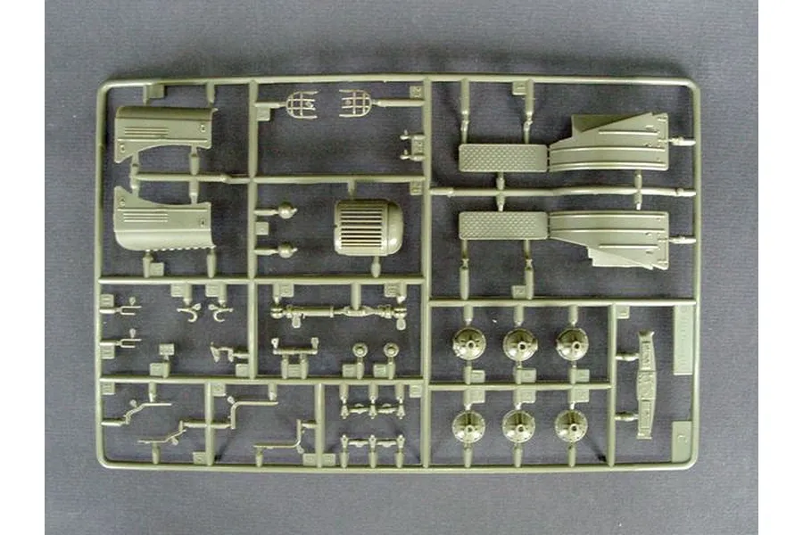 A single olive green plastic model kit sprue containing various vehicle parts, including fenders, wheels, and small structural components.