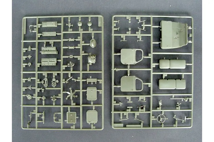 Two olive green plastic model kit sprues containing various vehicle parts, including doors, engine components, and interior pieces.