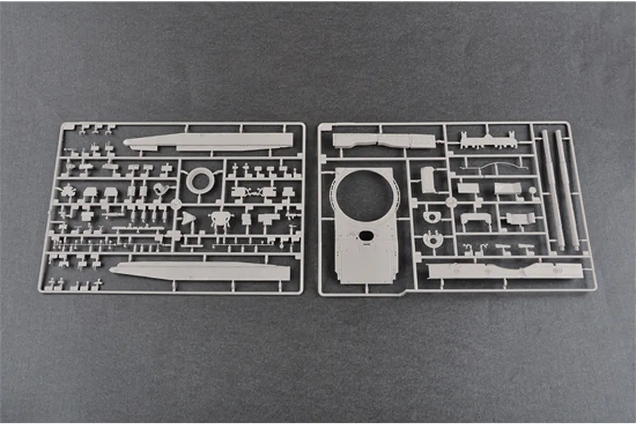 Two grey plastic model kit sprues containing various tank parts, including turret and hull components, laid out on a dark grey surface.