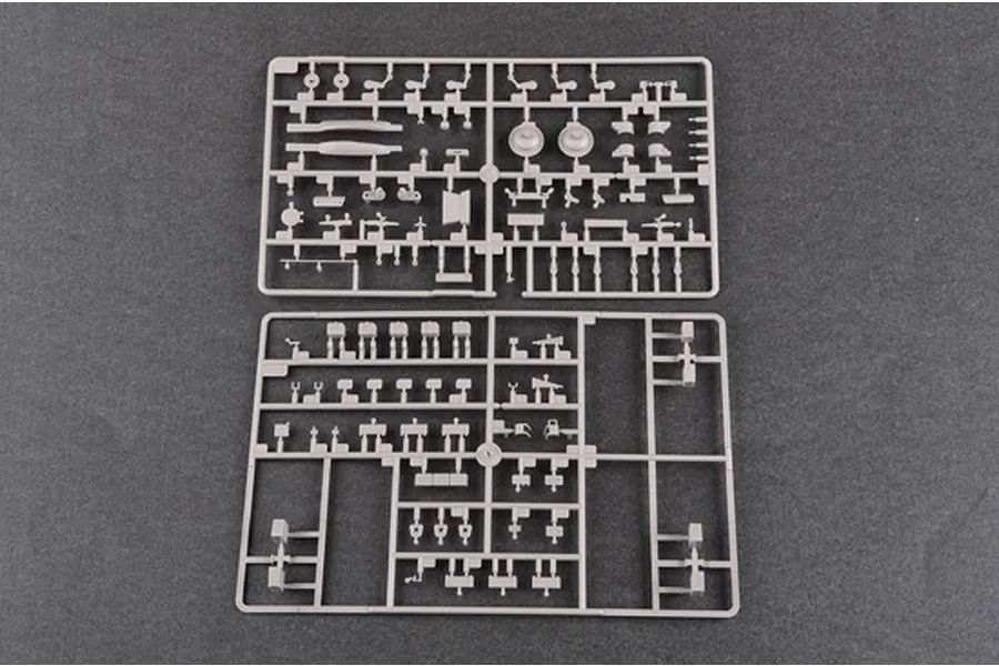 Two grey plastic model kit sprues containing various small tank parts laid out on a dark grey surface.