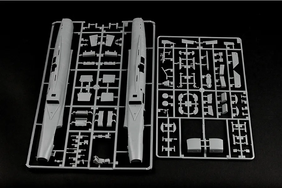 Two grey plastic model kit sprues showing fuselage halves and various aircraft components on a black background.