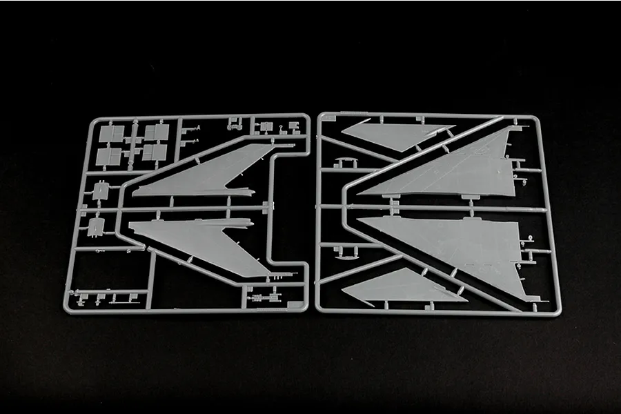 Two grey plastic model kit sprues containing aircraft wing and control surface parts against a black background.
