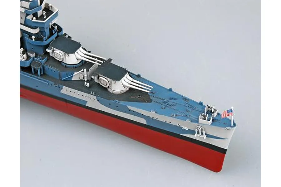 A high-angle view of the bow section of a 1/350 scale USS San Francisco CA-38 model ship, featuring camouflage paint, gun turrets, and a small US flag.