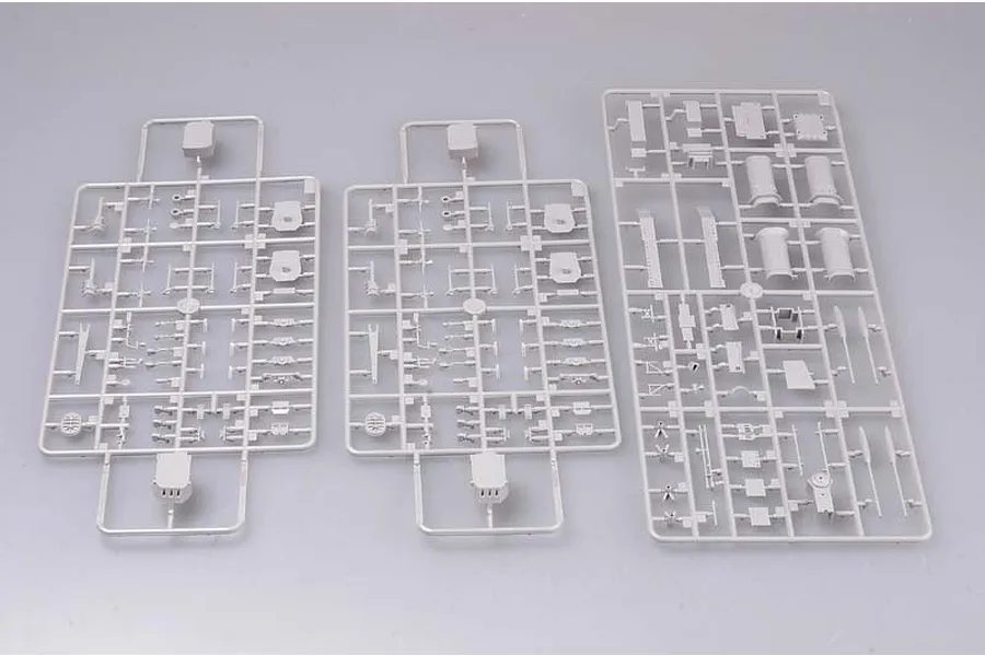 Three grey plastic model kit sprues containing various ship parts laid out on a plain light grey background.