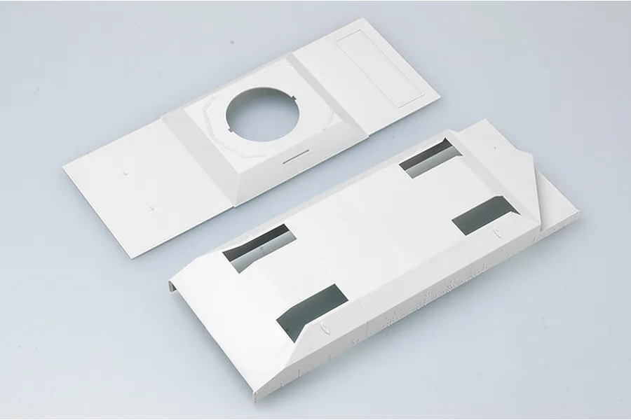 Two unpainted light grey plastic model kit parts for a military vehicle, likely a hull and deck section, viewed from above on a plain background.