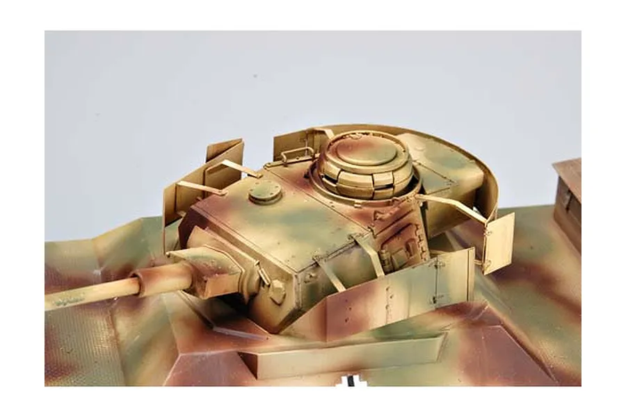 Close-up of a painted 1/35 scale model tank turret with camouflage paint and side armor plating on a white background.
