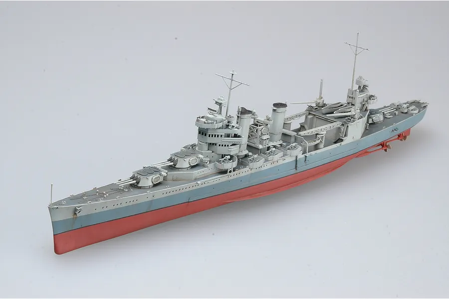 A high-angle studio shot of a 1/350 scale plastic model of the USS San Francisco CA-38 heavy cruiser, featuring a grey hull and red lower hull.