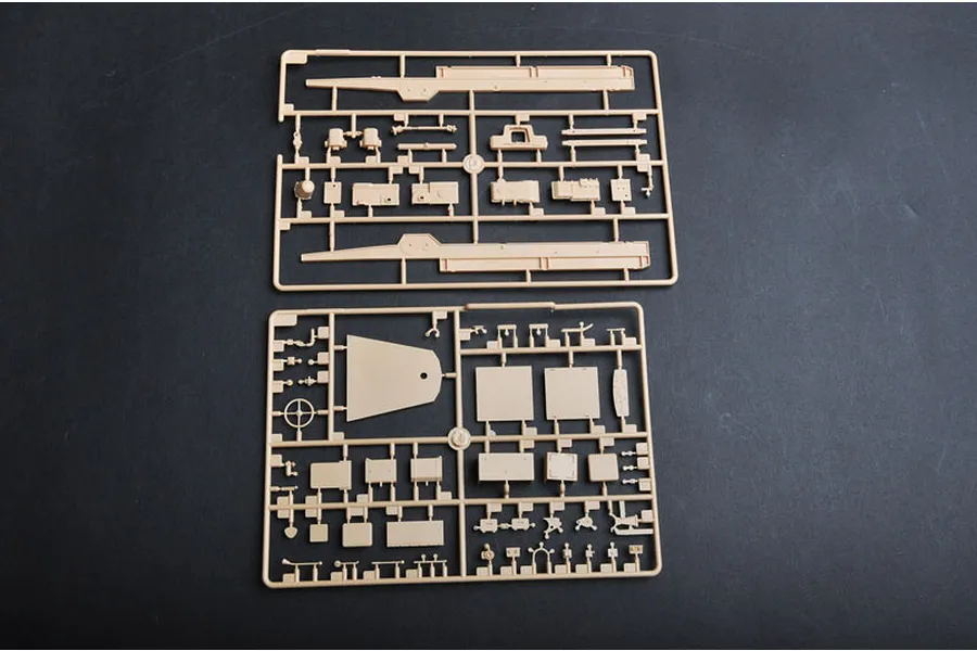 Two tan plastic model kit sprues containing various vehicle parts laid out on a dark surface.