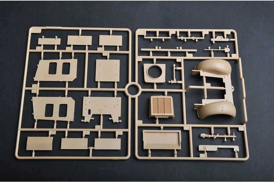 A tan plastic model kit sprue containing various vehicle body panels and parts for a 1/35 scale military model.
