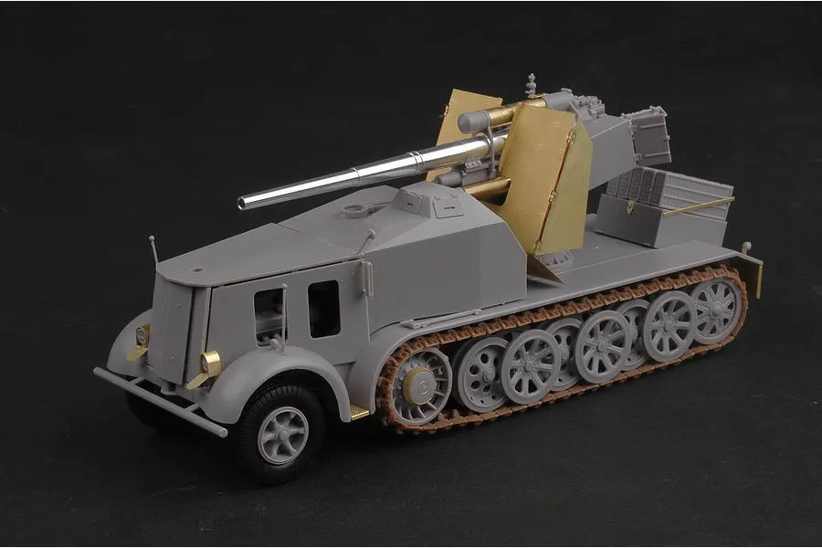 A 1/35 scale plastic model kit of a German 8.8cm Flak 18 half-track self-propelled gun, partially assembled in grey plastic with brass photo-etched parts.