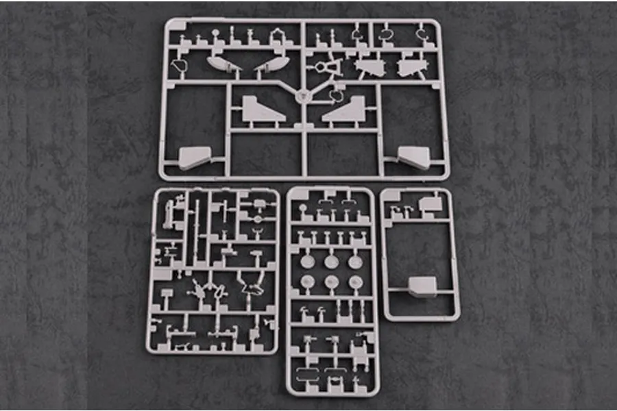 Four grey plastic model kit sprues laid out on a dark textured surface.
