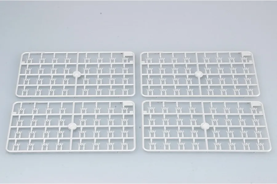 Four identical light grey plastic model kit sprues containing small tank track link parts on a plain light grey background.