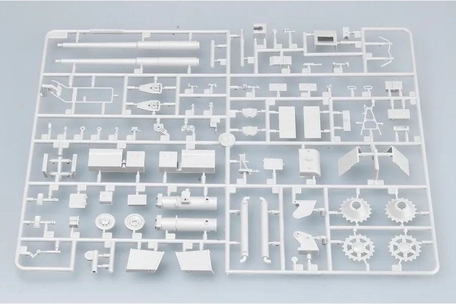 A grey plastic sprue containing various model kit parts for a 1/35 scale military vehicle, including gun barrels, wheels, and armor plates.