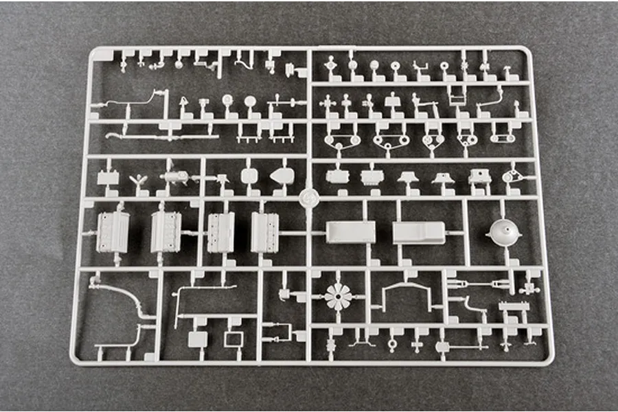 A light grey plastic sprue containing various small model parts for a 1/35 scale military vehicle kit, viewed from directly above on a dark grey surface.