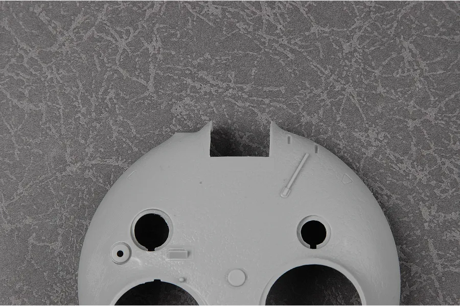 A grey plastic model tank turret component from a Trumpeter 1/35 scale T-62 model kit, viewed from above against a textured grey background.