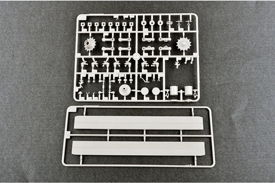 Two grey plastic model kit sprues containing various tank parts, including suspension components and side panels, on a dark grey background.