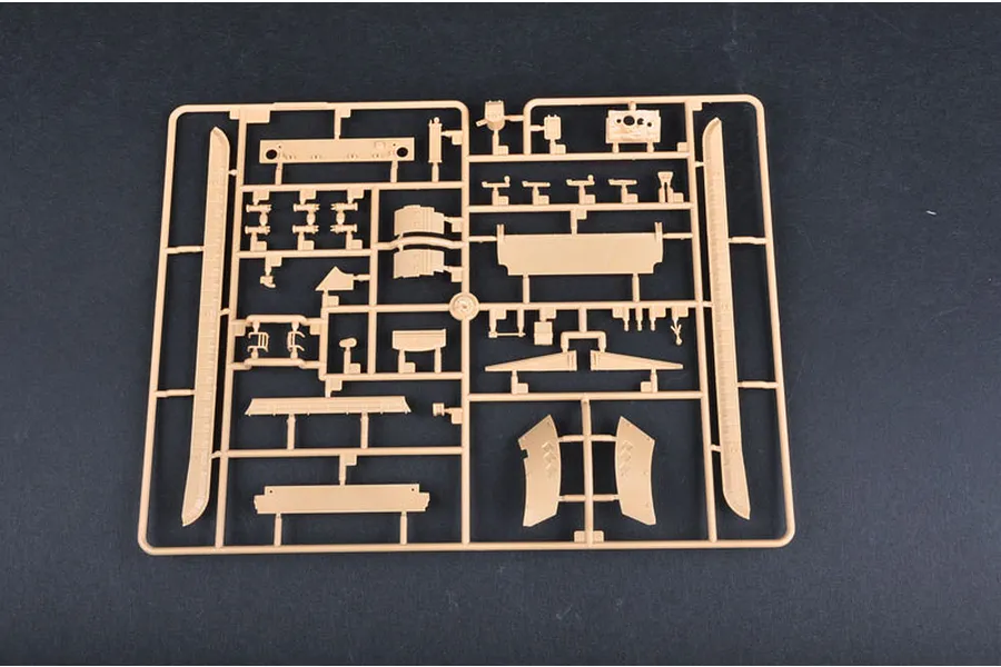 A tan plastic model kit sprue containing various unpainted tank parts on a dark grey background.