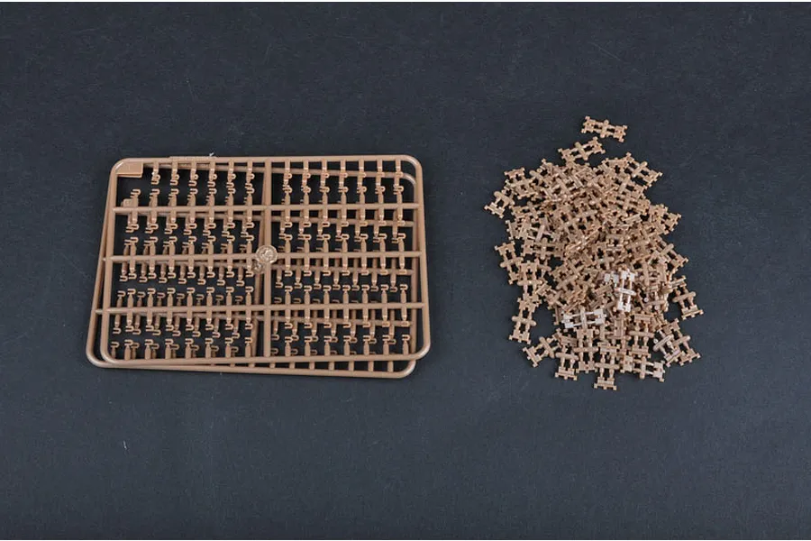 A plastic model kit sprue and a pile of individual track links for a 1/35 scale military vehicle model.