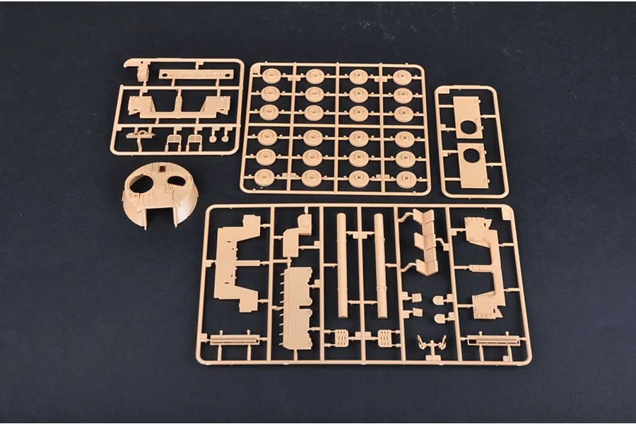 Tan plastic model kit sprues for a 1/35 scale military vehicle, including wheels, turret parts, and hull components on a dark background.