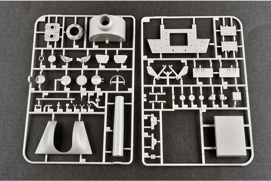 Two grey plastic model kit sprues containing various vehicle parts laid out on a dark surface.
