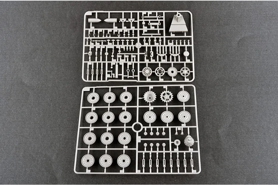 Two grey plastic model kit sprues containing various tank wheels, suspension parts, and small components on a dark background.