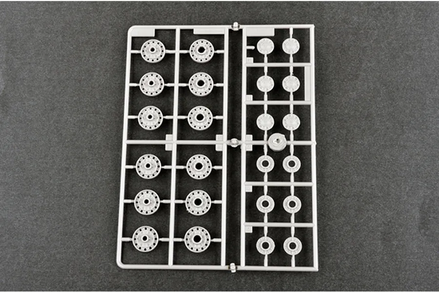 A grey plastic sprue containing various tank road wheels for a 1/35 scale model kit, viewed from above against a dark grey background.