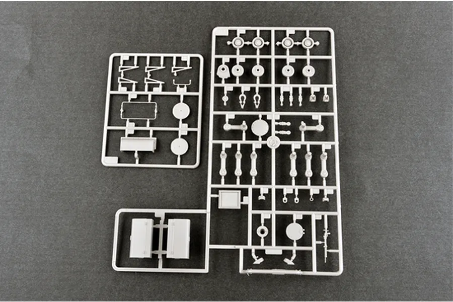 Three grey plastic model kit sprues containing various tank parts laid out on a dark grey surface.