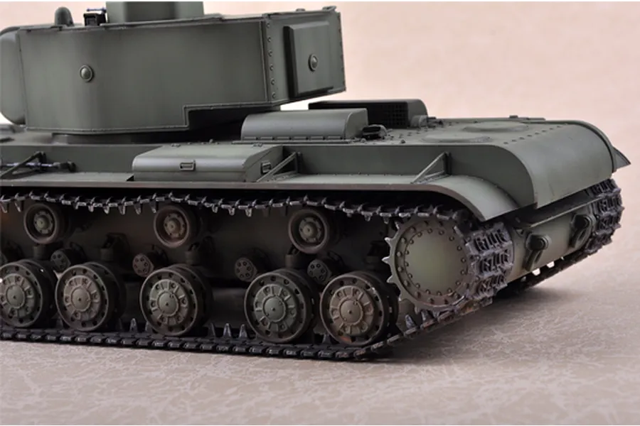 A close-up side view of a 1/35 scale model of a Russian KV-220 tank, showing the olive green hull, turret, and detailed track assembly.