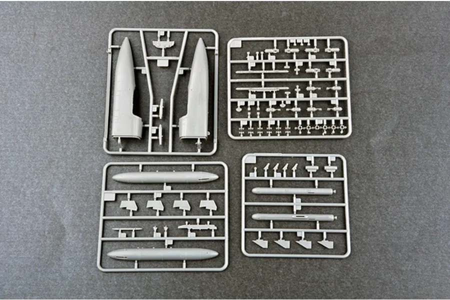 Four grey plastic model kit sprues containing aircraft fuselage and weapon parts for a 1/72 scale model kit.