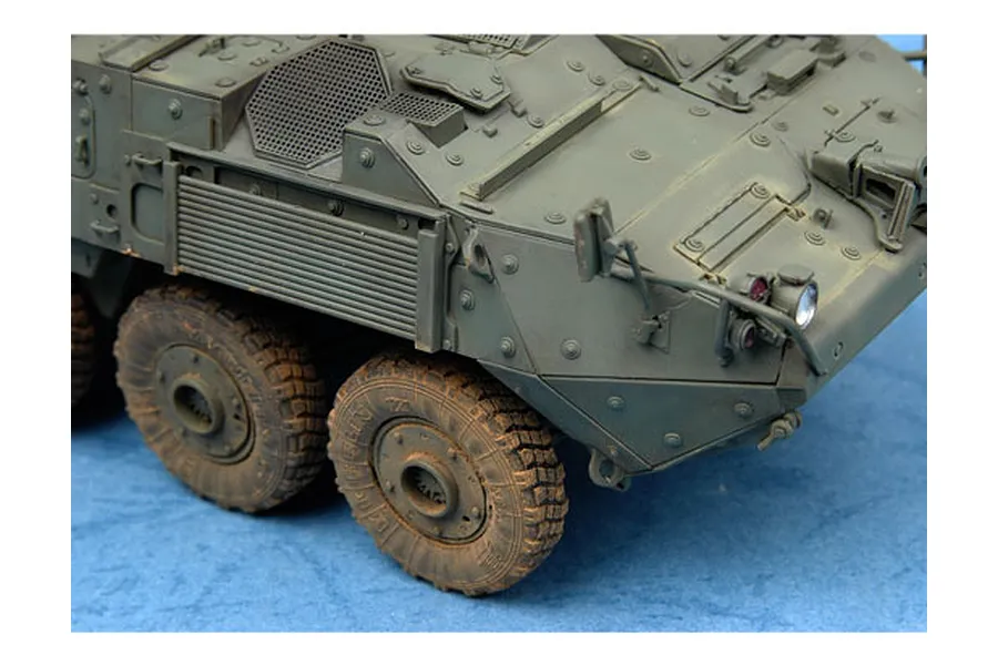 Close-up of a 1/35 scale model LAV-III armoured vehicle showing the front hull, side panels, and two wheels with weathered detailing.
