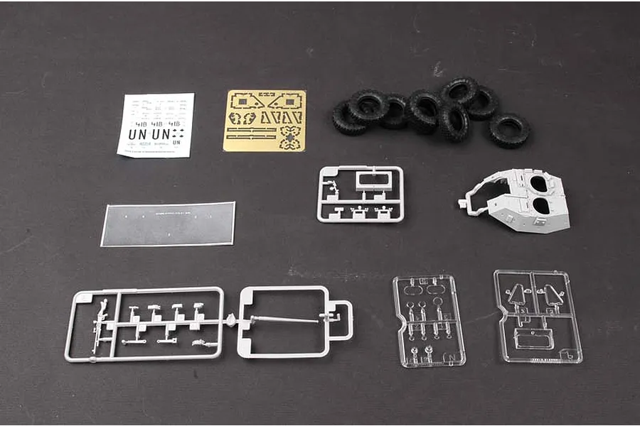 A selection of plastic model kit parts for a Trumpeter 1/35 LAV-III, including grey plastic sprues, rubber tires, a photo-etched metal sheet, and decals.