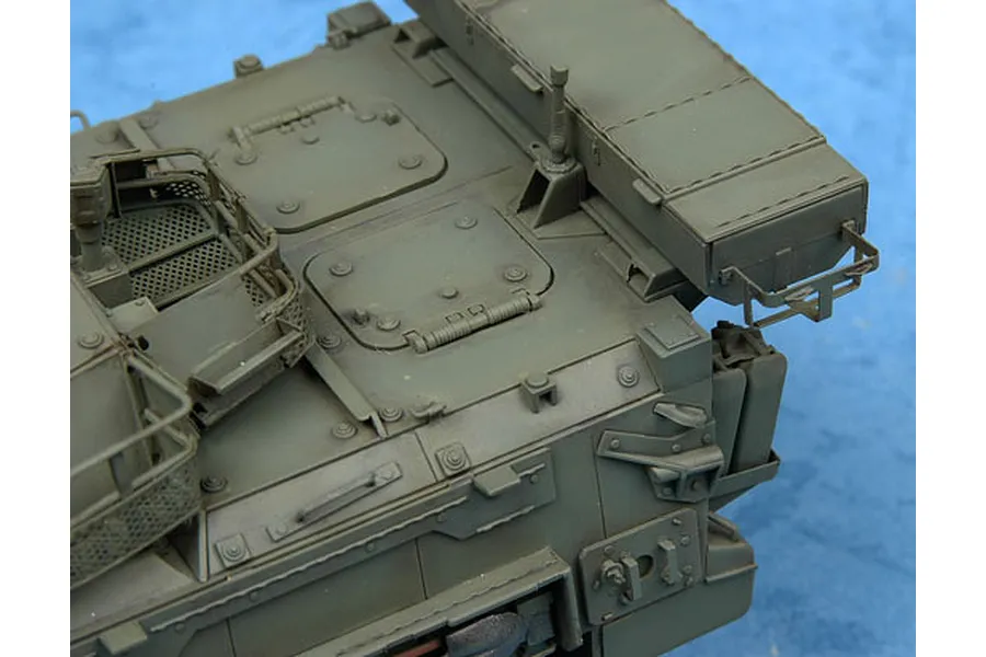 Close-up of the top deck of an olive green LAV-III military vehicle model kit, showing hatches, storage boxes, and mesh railings.