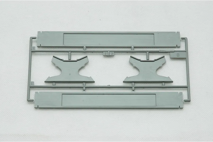 A grey plastic model kit sprue containing two display stand bases and two support cradles for a submarine model.