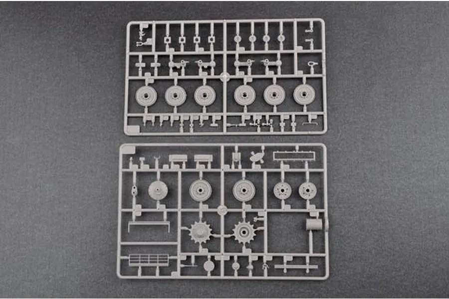 Two grey plastic model kit sprues containing tank wheels, sprockets, and small mechanical parts on a dark grey background.