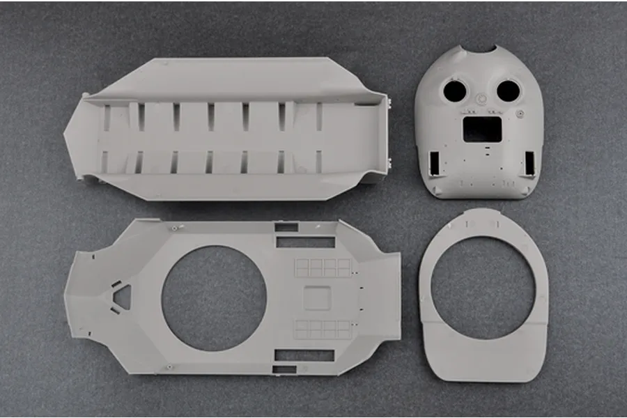 Top-down view of unpainted grey plastic model tank hull and turret components on a dark grey background.