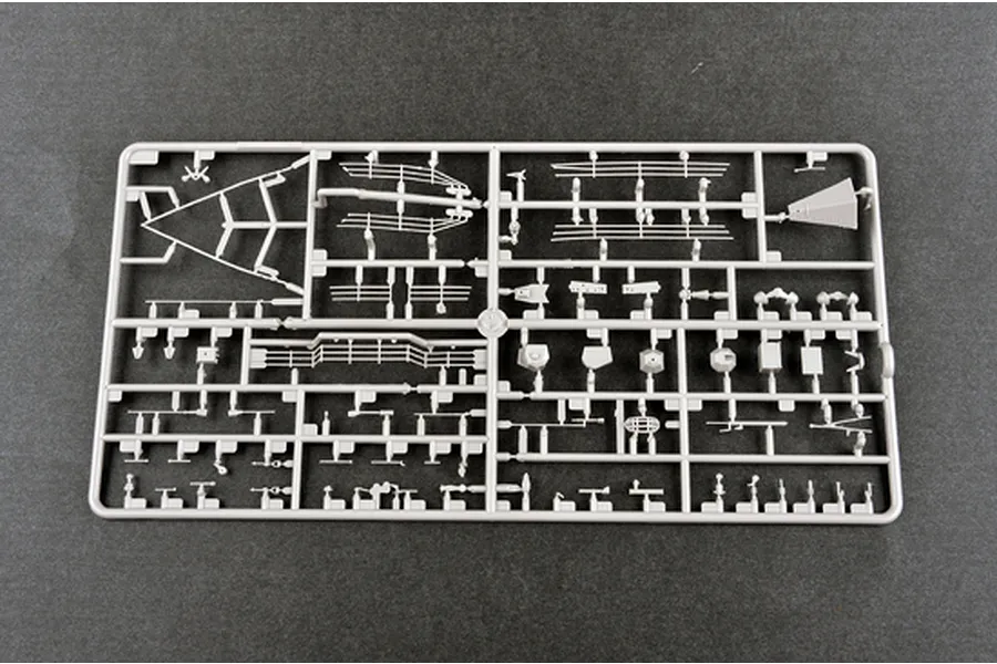 A grey plastic sprue containing various small model parts for the Trumpeter 1/35 U.S. M1083 FMTV model kit, set against a dark grey background.
