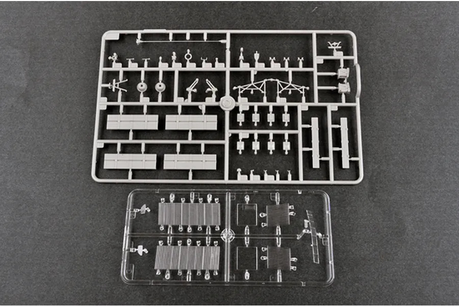 Two plastic model kit sprues, one grey and one clear, containing various small parts for a 1/35 scale military vehicle model.