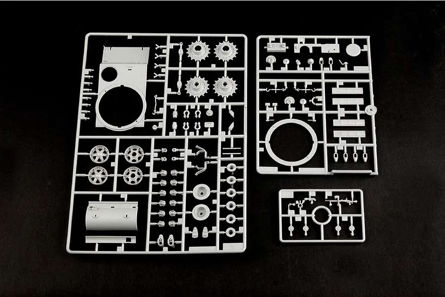 Three grey plastic model kit sprues containing various tank parts, including wheels, turret components, and hull sections, laid out on a black background.