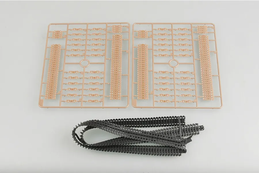 Two tan plastic sprues containing individual tank track links and a long strip of flexible black rubber tank tracks for a model kit.