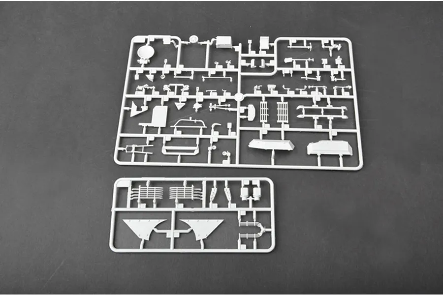 Two grey plastic model kit sprues containing various tank parts on a dark grey surface.