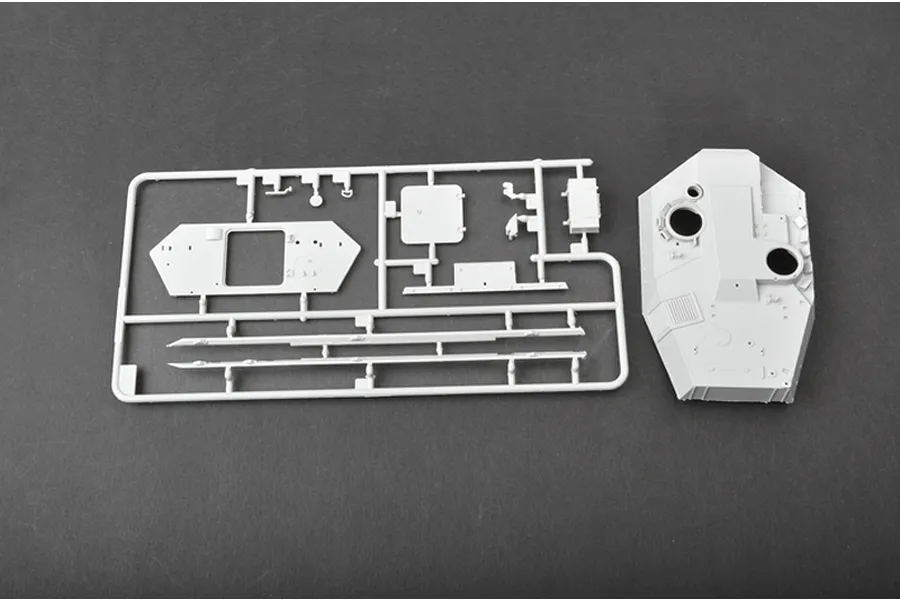 A light grey plastic model tank sprue and a separate tank turret component on a dark grey background.