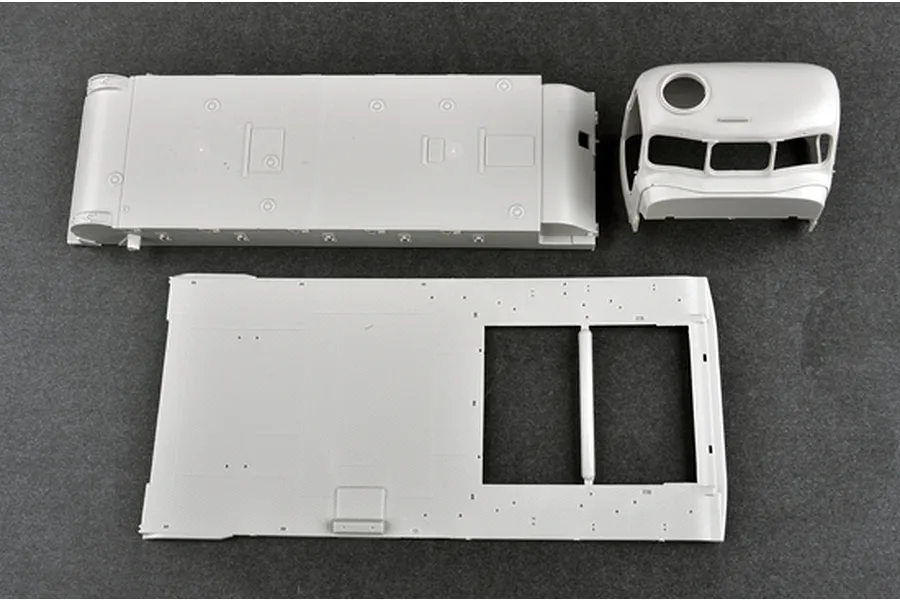 Unassembled grey plastic model kit parts for a 1/35 scale Russian AT-T artillery tractor, including the main hull, cabin, and chassis base.