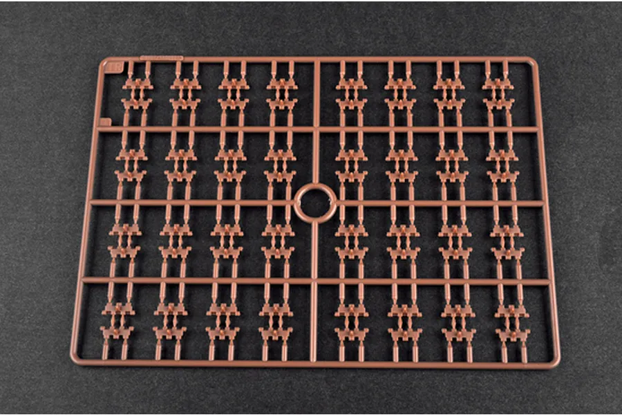 A brown plastic sprue containing numerous small track link parts for a 1/35 scale model kit, set against a dark grey background.