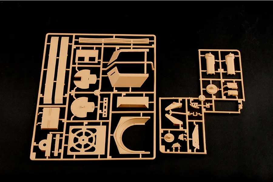 Two tan plastic model kit sprues containing various vehicle parts for a 1/35 scale military model on a black background.