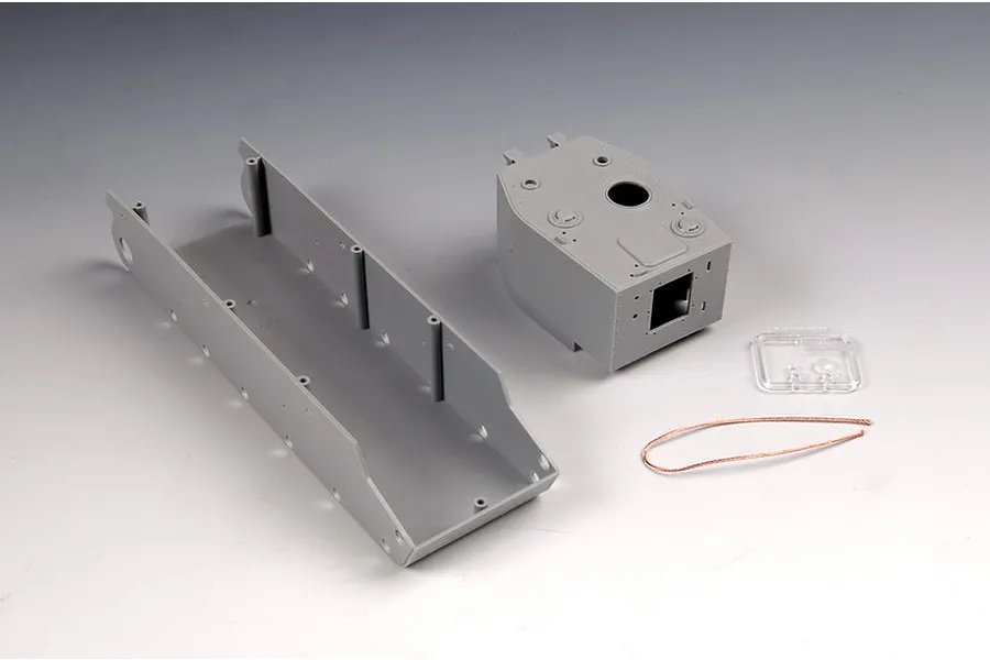 Unassembled grey plastic tank hull and turret parts for a 1/35 scale model kit, including a small clear part and a length of copper wire.