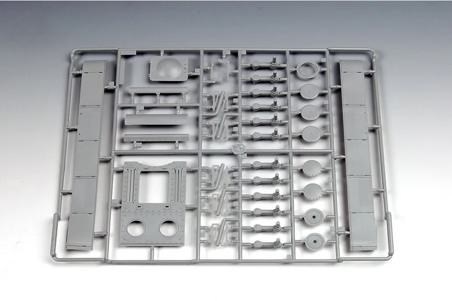 A grey plastic sprue containing various tank parts for a 1/35 scale model kit, including suspension arms, wheels, and hull plates.